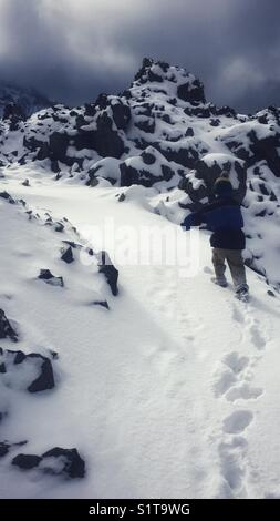 Junge Junge auf einem schneebedeckten Weg durch den grossen Obsidian flow bei Newberry Volcanic National Monument Stockfoto