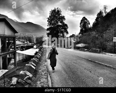 Ein Mädchen geht auf Kullu Manali highway Stockfoto