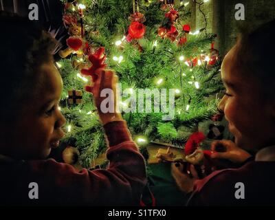 Kinder, die Spaß daran haben, ihren Weihnachtsbaum zu dekorieren. Stockfoto