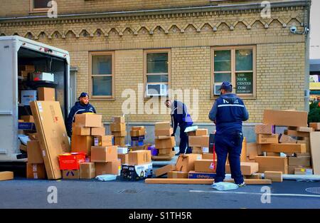 Arbeitnehmer entladen Pakete und Kartons von FedEx Lkw in Midtown New York City während der Weihnachten Rush, USA Stockfoto