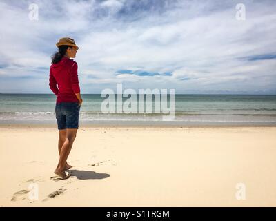 Attraktive junge Frau in rosa Shirt und Shorts, wachen am Strand Stockfoto