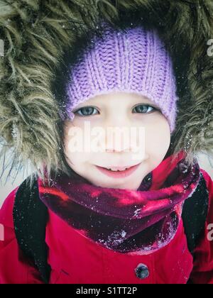 Portrait von 5 Jahre alten Mädchen mit schneeanzug mit pelzigen Motorhaube draußen im Schnee Stockfoto