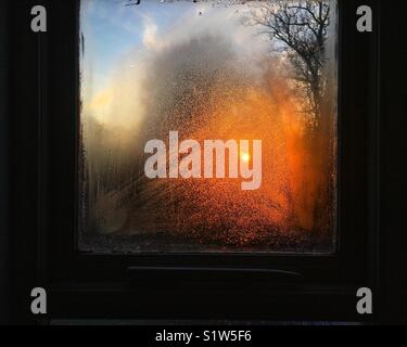 Winter Sonnenaufgang durch Kondensation im Fenster Stockfoto