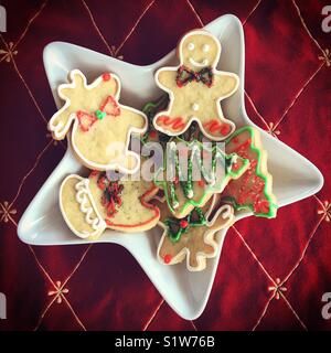 Festliche geschmückten Sugar Cookies auf einem sternförmigen Platte auf roten Hintergrund. Platz crop. Stockfoto