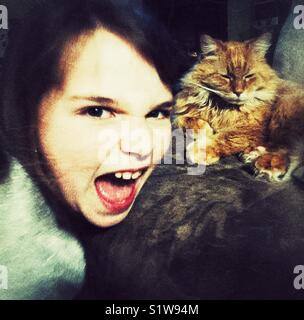 Böse Mädchen kreischen mit entspannten orange Katze im Hintergrund Stockfoto