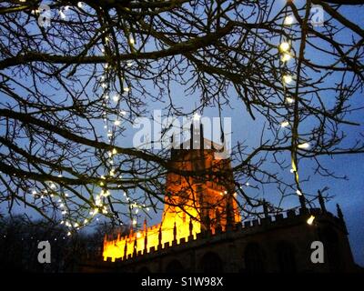 Flutlicht Cotswold Kirche mit Lichterketten an einem Baum auf dem Friedhof in Großbritannien Stockfoto