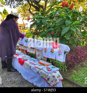 Frau verkaufen handgefertigte Madeira Spitzen aus einer Bank in der städtischen Gärten zur Weihnachtszeit. Funchal, Madeira, Portugal Stockfoto