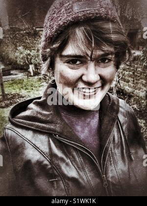 Junge Frau trägt eine braune Lederjacke und Wollmütze, H&S Portrait im Freien. Stockfoto