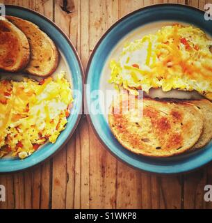 2 Frühstück Platten von Gemüse Omelett mit geschmolzenem Käse und Roggen Toast auf einen hölzernen Tisch Stockfoto