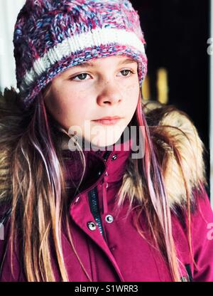 Porträt der 10 Jahre alte Mädchen mit lila Haaren streifen tragen Winter Mantel und Hut stricken an der Seite suchen Stockfoto