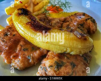 Degenfisch mit Pommes frites, gekrönt mit einem gebratenen Bananen. Ein typisches Gericht aus Madeira, Portugal Stockfoto