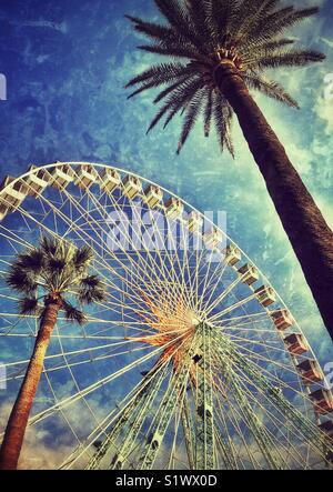 Eine Farbe grunge Effekt Bild des großen Riesenrad in der Gegend von Nizza die Place Massena & Albert's 1. Garten, Còte ein 'Azure, Frankreich. Die Aussicht ist durch zwei Palmen ergänzt. Foto © COLIN HOSKINS. Stockfoto
