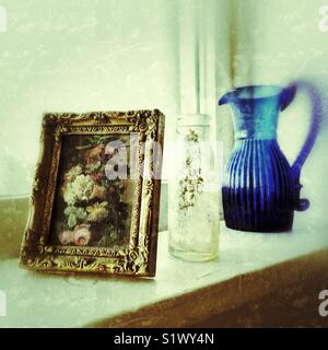 Nostalgische Shabby Chic noch Leben auf der Fensterbank mit antiken blaues Glas Krug, staubigen Glas Milch Flasche und floralen Malerei in gold rahmen Stockfoto