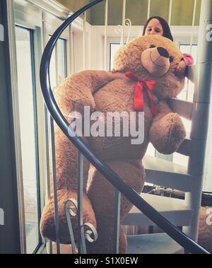 Kleines Mädchen mit riesigen Überdimensionierten braun gefüllte Teddybär auf Wendeltreppe Stockfoto