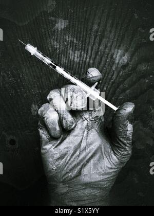 Behandschuhte Hand, die eine Nadel Stockfoto