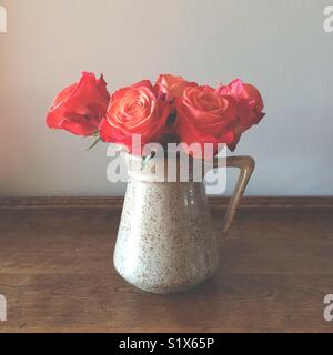 Orange rote Rosen in einem Krug Stockfoto