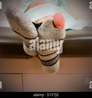 Ist ein Junge Big Toe peeking aus einem Loch in seinem Socken im Büro des Doktors. Stockfoto