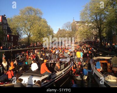 Amsterdam während Koningsdag, ein niederländischer nationaler Feiertag. Auf den Kanälen gibt es viele kleine Boote mit Menschen feiern. Stockfoto