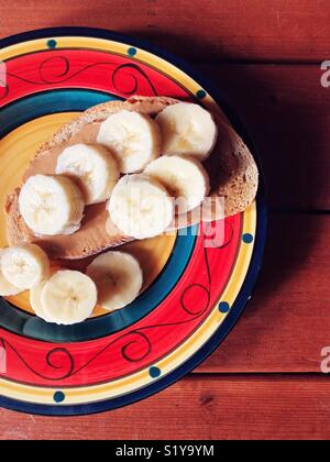 Bunte Platte mit Bananenscheiben und Erdnußbutter auf Roggen toast Stockfoto