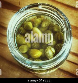 Eingelegte kapern im Glas auf einem hölzernen Tisch in natürlichem Licht Stockfoto