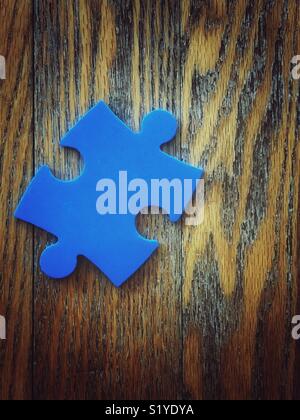 Einzelne blaue Puzzleteil auf Holz Eiche Boden Stockfoto