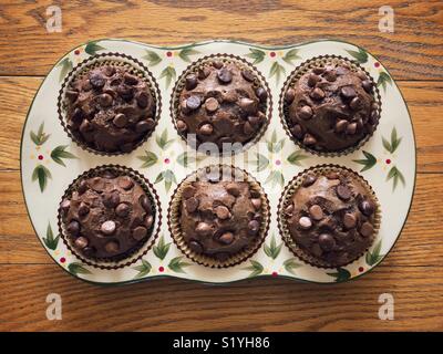 Banane Schoko Muffins gebacken in einem floralen Keramik Topf auf einem hölzernen Oberfläche Stockfoto