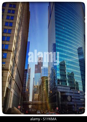 Chicago erhöhte "El" Zug geht durch die Chicago Loop auf seine erhöhte Track, obwohl es durch die massiven Wolkenkratzern, einschließlich der Wills "Sears Tower" in den Schatten gestellt. Stockfoto