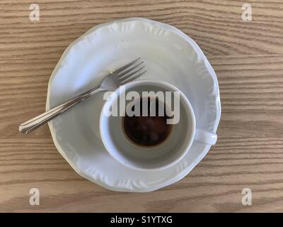 Leeren Teller und Tasse Kaffee und eine Gabel über eine Holz Tisch Stockfoto