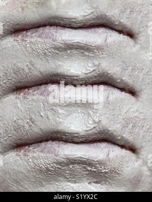 Ein abstraktes Bild von drei Sets von Lippen, der auf ein Gesicht Tragen eines weißen Ton Schlamm Maske
