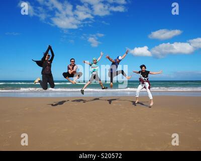 Freunde Spaß springen auf einem Strand an einem sonnigen Tag Stockfoto