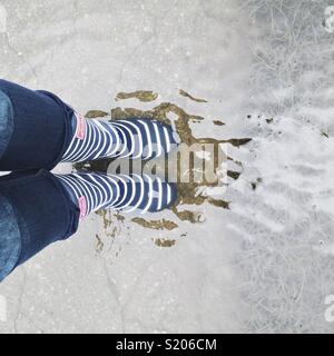 Person tragen regen Stiefel Pfütze Stockfoto