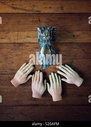 Hand geformt Vintage bronse Türklopfer auf Holz durch vier kleine Fingerpuppen Kunststoff Hände - Gehorsam Konzept umgeben Stockfoto