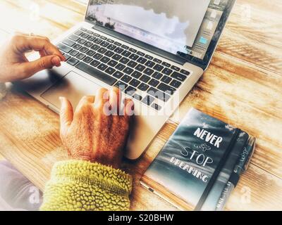 Frau mit einem Notebook, mit einem Notebook neben ihr, nie aufhören zu träumen Stockfoto