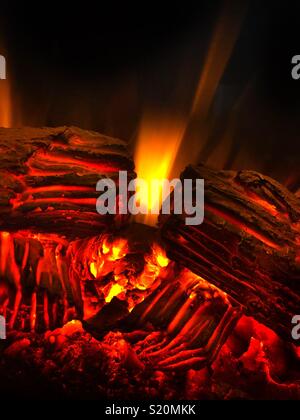 Heiße rote und gelbe Flammen gegen einen dunklen Hintergrund in einem faux Kamin Heizung. Stockfoto