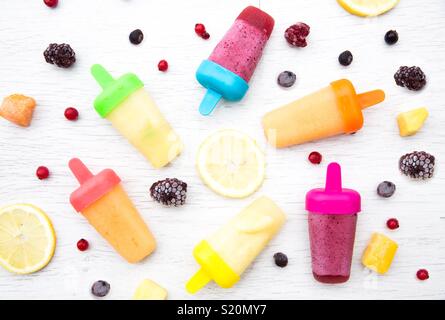 Ein flach Essen Bild von bunten Früchten aromatisiert Eis Lutscher von frischen Früchten Zutaten auf einem weißen Hintergrund umgeben. Stockfoto