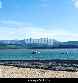 Anzeigen von Beaumaris Strand über die Menai Straits nach Snowdonia. Stockfoto