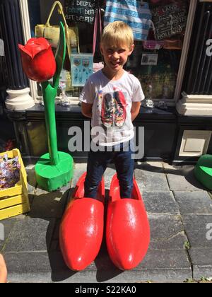 Kind stehen in riesigen Clogs in Amsterdam an einem sonnigen Sommertag Stockfoto