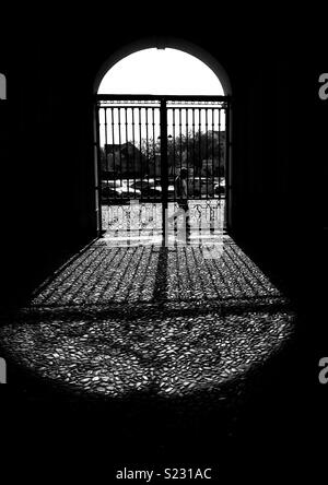 Silhouette der Mann hinter einem Tor und die Schatten auf den Boden werfen Stockfoto