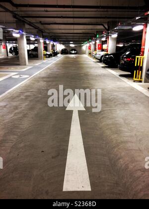 Ein weißer Pfeil weist den Weg in eine Tiefgarage Stockfoto