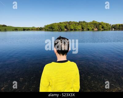 Junge in der gelben Brücke mit Blick auf einen See Stockfoto