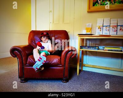 Ein kleiner Junge sitzt eine grosse, bequeme Ledersessel in einem Zahnarzt, der darauf wartet, von Zimmer. Stockfoto
