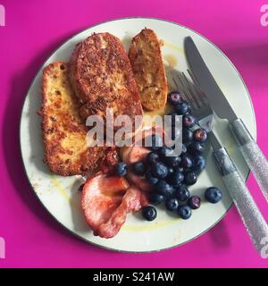 Hausgemachte brunch der French Toast, Speck, Blaubeeren und Ahornsirup. Auf einem vintage Platte mit glitzerndem Besteck auf ein shocking Pink Küchenarbeitsplatte serviert! Stockfoto