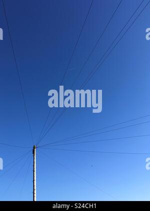 Telegraphenmast und die Drähte gegen einen tiefen blauen Sommerhimmel Stockfoto