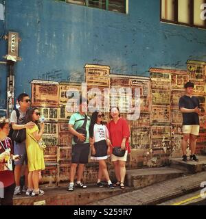 Chinesischer Touristen posieren für Fotos vor ein Wandbild von Alex Croft in Graham Street, Soho, Central, Hong Kong Island Stockfoto