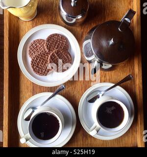 Blick von oben auf einen hölzernen Tee Tablett mit zwei Tassen, silber Tee, Kekse und Milch in einem Keramik Krug Stockfoto