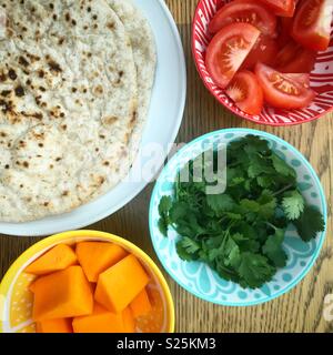 Curry Vorbereitung mit butternut squash, Koriander, Tomaten und chapati Stockfoto