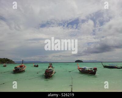 Long-tail taxi Boote am türkisblauen Meer bei bewölktem Himmel in Koh Lipe, Thailand Stockfoto