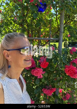 Frau genießen Sie die herrliche rote Rosen. Stockfoto