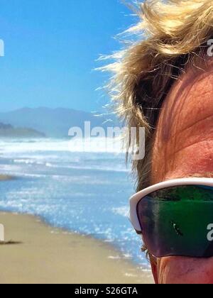 Blonde Surfer mit Sonnenbrille auf einer nördlichen Kalifornien Strand im Sommer mit Coastal Mountains, Sand und Surfen. Stockfoto
