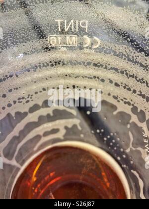 Ansicht von innen mit einer fast leeren Bier Glas, auf einem pub Gartentisch, die restlichen Schaum Ringe als Bier getrunken hat. Das Wort Pint in umgekehrter Reihenfolge auf der Seite des Glases gezeigt wird. Stockfoto